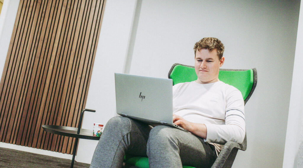 medewerker op een stoel, werkend met zijn laptop