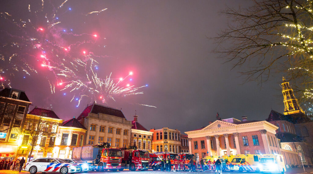 Jaarwisseling met de hulpdiensten op de voorgrond en de korenbeurs op de achtergrond.