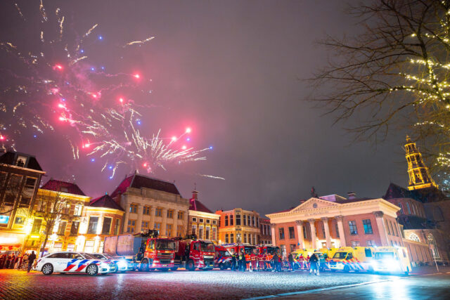 Jaarwisseling met de hulpdiensten op de voorgrond en de korenbeurs op de achtergrond.